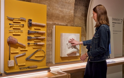 Une personne touche une statue au musée afin d'en comprendre sa forme